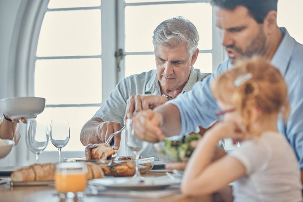 Φαγητό, τραπεζαρία και ηλικιωμένος άνδρας με την οικογένειά του απολαμβάνουν ένα γεύμα μαζί στο σύγχρονο σπίτι τους. Πατέρας, κορίτσι παιδί και παππούς στη συνταξιοδότηση έχουν φαγητό στο εορταστικό δείπνο, μεσημεριανό γεύμα ή εκδήλωση - Φωτογραφία, εικόνα