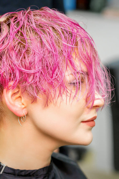 Beautiful young caucasian woman receiving new short pink hairstyle in hairdresser salon - Photo, Image
