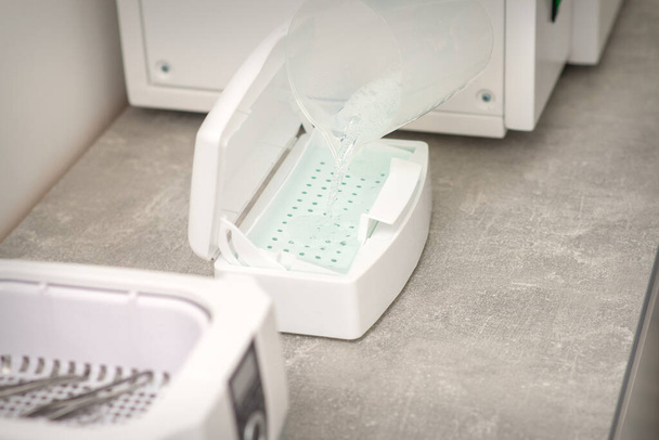 Додавання рідини для дезінфекції інструментів до машини для стерилізації інструментів
 - Фото, зображення