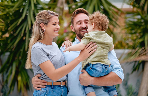 Family, love and parents with child in garden with smile, happy and hug together in summer. Excited, relax and loving mother and father on outdoor holiday with a kid in a park, nature or backyard. - Фото, зображення