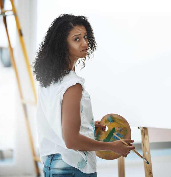 Нельзя принуждать к искусству. Портрет молодой женщины, которая выглядит расстроенной, пытаясь рисовать дома на холсте - Фото, изображение