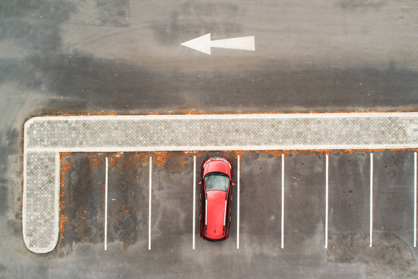 Widok z góry na czerwony samochód SUV zaparkowany na parkingu betonowym z białą linią znaków drogowych na ulicy. Powyżej widoku samochodu z rzędu na miejscu parkingowym poza parkingiem - Zdjęcie, obraz