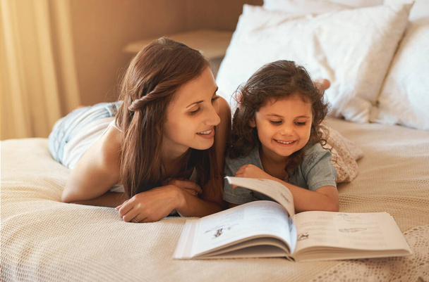 Es ist noch nicht Schlafenszeit. eine glückliche Mutter und Tochter zu Hause beim Lesen eines Märchenbuchs auf dem Bett - Foto, Bild
