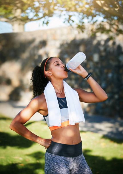 Zatrzymuję się, żeby zatankować. sportowa młoda kobieta pijąca wodę podczas ćwiczeń na zewnątrz - Zdjęcie, obraz