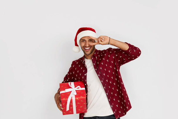 Happy Man Holding Present. Excited Multiracial Guy Holding in Hands Wrapped Present Box with Excitement. New Year Concept. Indoor Studio Shot White Background  - Foto, Imagem