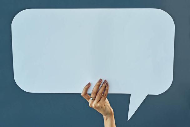 Say it right here. Cropped studio shot of a woman holding up a blank speech bubble against a gray background - 写真・画像
