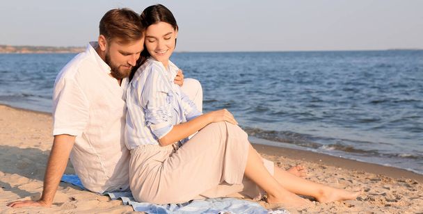 Glückliches junges Paar sitzt am Strand - Foto, Bild