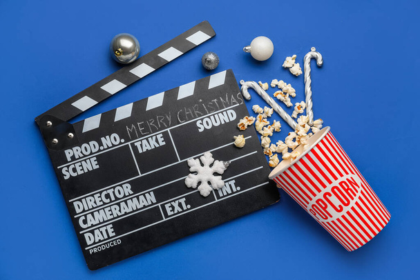 Film clapper, seau de pop-corn et boules de Noël sur fond bleu - Photo, image