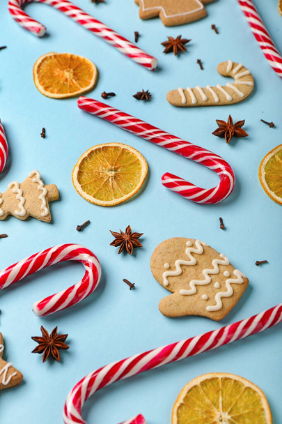 Skład ze smacznymi laskami cukierkowymi, ciasteczkami, przyprawami i suszonymi plastrami pomarańczy na tle koloru - Zdjęcie, obraz