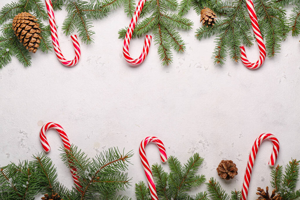 Composition with sweet candy canes and fir branches on light background - Foto, afbeelding