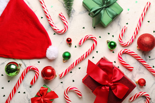 Composición con bastones dulces de caramelo, regalos de Navidad, bolas y sombrero de Santa sobre fondo claro - Foto, imagen