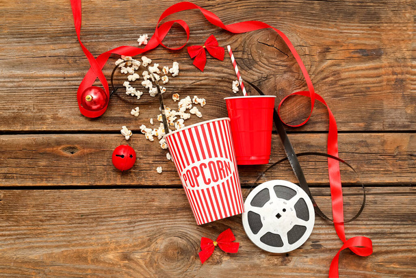 Bucket of popcorn with cup, film reel and Christmas decor on wooden background - Foto, afbeelding