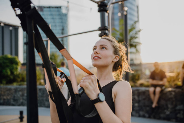 Happy young woman doing exercises at outdoor work-out city park. - Fotó, kép