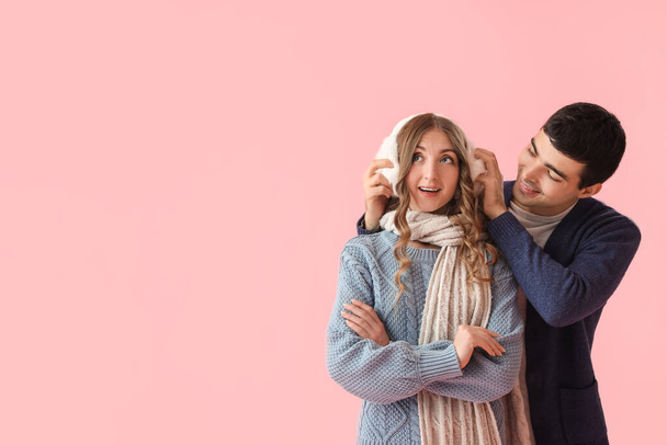 Loving couple in warm clothes on pink background - Photo, Image