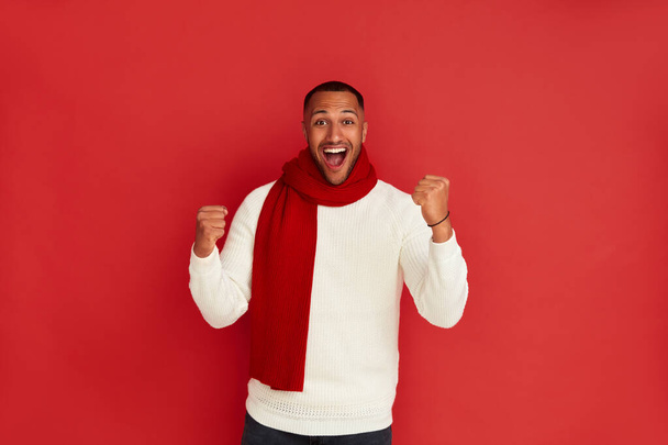 Winner Man Rejoicing Studio. Extremely Happy Multiracial Guy Raised Arm Gesturing Yes I Did It, Im Winner, Feeling Energetic and Lively. Isolated on Red Background  - Foto, immagini