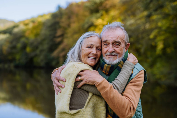 Senior couple in love huging each other in autumn forest. - 写真・画像