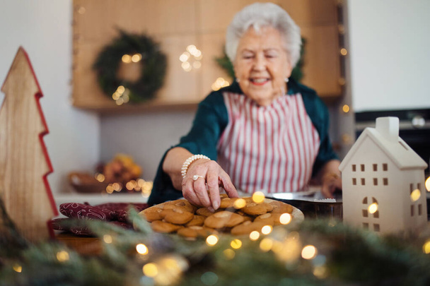 Happy senior woman baking a Christmas cakes at home. - Foto, Bild