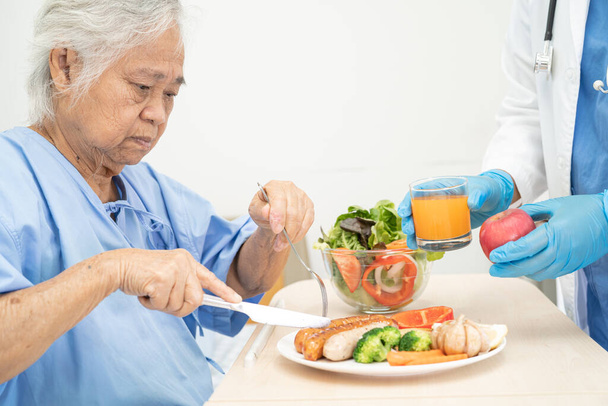Asiatico anziano o anziano donna anziana paziente mangiare colazione e verdura cibo sano con speranza e felice mentre seduto e affamato sul letto in ospedale. - Foto, immagini