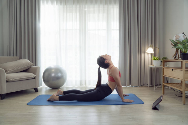 Donna asiatica esercizio e stretching nella sua camera da letto, il suo tentativo di rendere sottile da prendere Yoga, cardio, fitness a casa tra quarantena - Foto, immagini