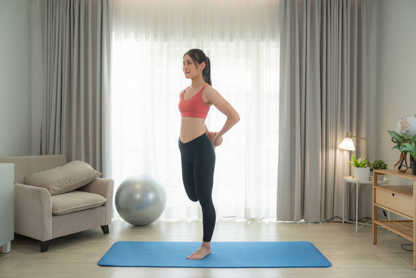 Asian woman exercise and stretching in her bed room, her try to make slim by take Yoga, cardio, fitness at home between quarantine - Photo, image