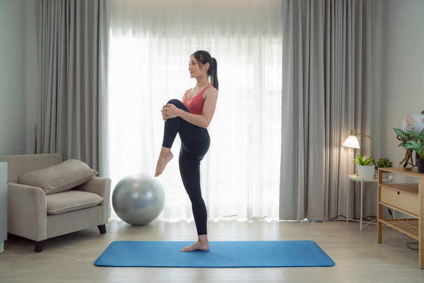 Азиатская женщина упражнения и растяжения в своей спальне, ее пытаются сделать тонкий, взяв йогу, кардио, фитнес дома между карантином - Фото, изображение