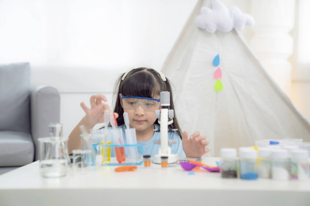 Азійська дівчинка, яка робить домашню роботу, проводячи хімічний експеримент у себе вдома, ця фотографія може бути використана для освіти, дитини, школи та студентської концепції. - Фото, зображення
