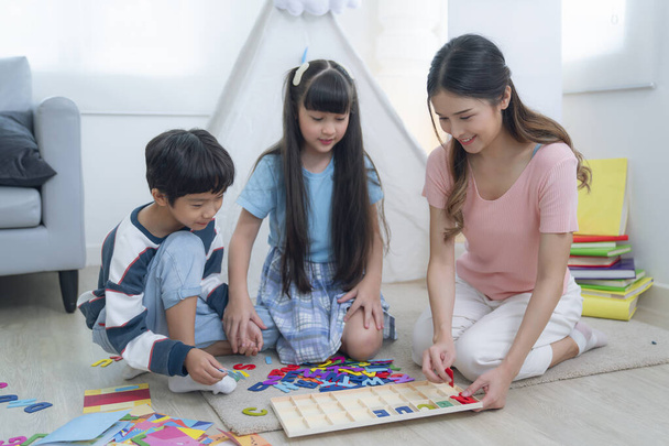 Asiatico madre giocare e imparare insieme con suo som e suo figlia in soggiorno, essi giocare testo blocco insieme - Foto, immagini