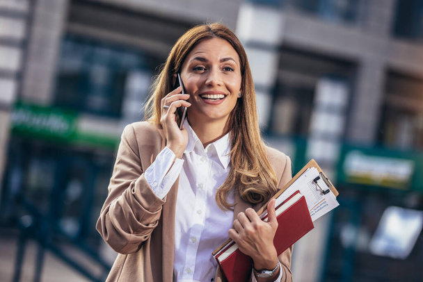 Successful business woman talks on the phone outdoors - Fotó, kép