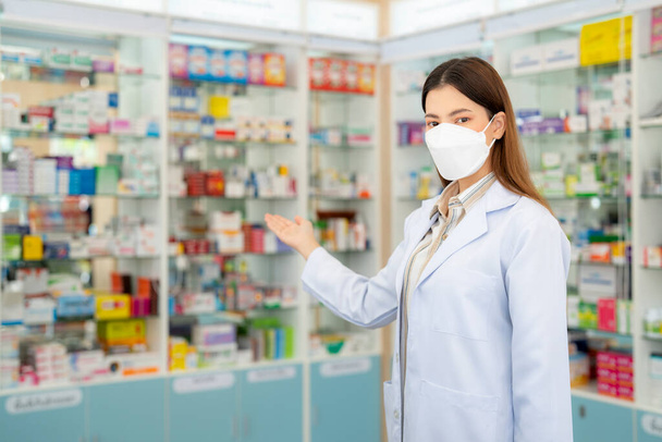 Mujer farmacéutica asiática con máscara de protección en farmacia de su negocio para la venta de una droga y farmacia con su cliente - Foto, imagen