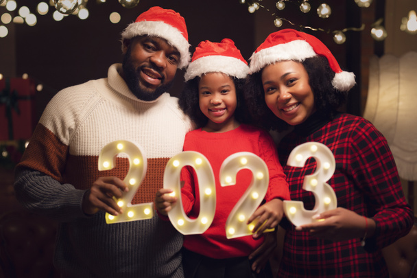 Familia americana en 2023 fiesta de año nuevo y feliz Navidad con 2023 número de texto en la mano en su casa - Foto, imagen