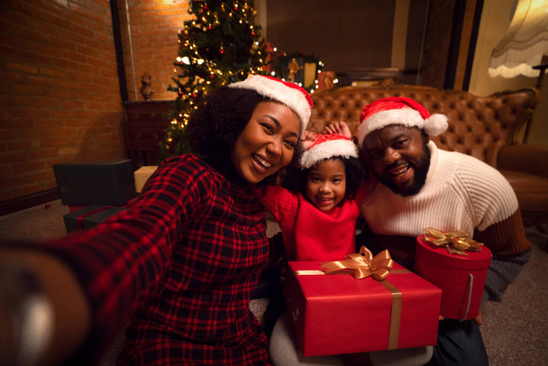 Amerykańska rodzina w 2023 roku przyjęcie noworoczne i Wesołych Świąt z pudełka na rękę w domu - Zdjęcie, obraz