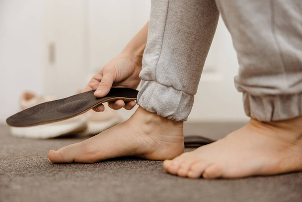 Flat feet diagnosis and orthotics, shoe inserts. Problems with flatfoot, pain. Identification of flat foot. Treatment to plantar fasciitis. Womans foot and insoles at home, close up view - 写真・画像
