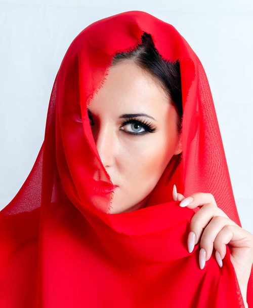 Portré egy fátyolos lányról. Vörös fátyol borítja az arcot.. - Fotó, kép