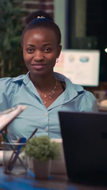Verticale video: Afro-Amerikaanse zakenvrouw lacht portret in zakelijke bijeenkomst, collega 's praten in bestuurskamer, slow motion. Diverse collega 's, vrouw op zoek naar camera, slow motion medium shot - Video