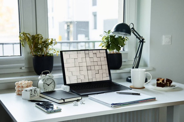 Arbeitsplatz im Home Office. Tisch mit Laptop, Notizbuch und heißem Kaffee neben Fenster im Wohnzimmer. - Foto, Bild
