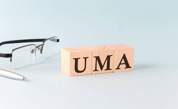 Testo UMA scritto su cubi di legno su sfondo blu - Foto, immagini