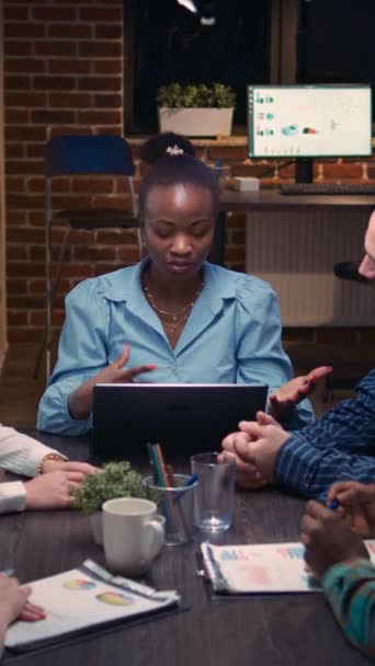 Vertical video: Diverse coworkers brainstorming, listening to executive in business meeting, discussing presentation. African american businesswoman talking, team leader speaking in office at night - Footage, Video