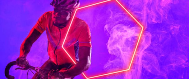 Afrykański amerykański kolarz jeżdżący na rowerze z oświetlonym sześciokątem na fioletowym tle. Kopiuj przestrzeń, kompozyt, sport, konkurencja, neon, ilustracja, świecący, dym i abstrakcyjny pojęcie. - Zdjęcie, obraz
