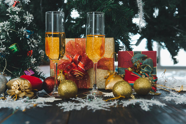 2023 Boldog új évet, Karácsonyi ünnepség pezsgős poharakkal, ajándékok, fenyő fa, gyertya, labda dekoráció háttér. - Fotó, kép