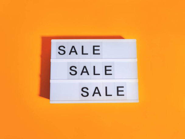 Sale store concept with lightbox words on orange background. Trendy flat lay with hard shadows - Zdjęcie, obraz