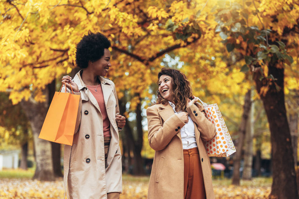 Onnellinen nainen ystäviä kävely metsässä syksyllä ostoskassit. - Valokuva, kuva