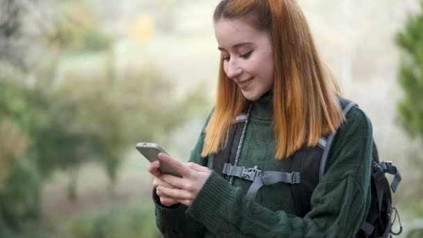 Felice rossa giovane escursionista donna consulenza smartphone durante il trekking. concetto di escursionismo. - Filmati, video
