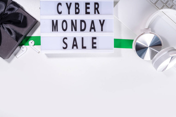 Cyber monday sale background. Simple white flat lay with lightbox "Cyber monday", gift boxes, shopping cart, laptop, tablet, headphones top view copy space. Online holiday shopping concept - Foto, Imagem