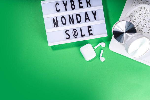 Cyber Monday продається по всьому світу. Проста яскраво-зелена площина лежала з коробкою з блискавками "Cyber Monday", подарунковими коробками, кошиком для покупок, ноутбуком, планшетом, навушниками. Концепція інтернет-магазинів - Фото, зображення