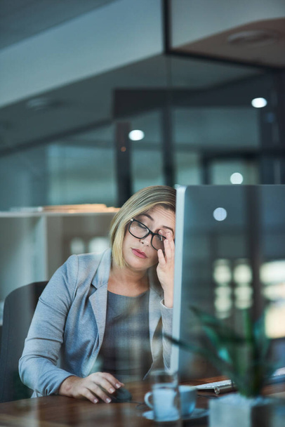 Die Anstrengung spüren. eine Geschäftsfrau sieht gestresst aus, während sie spät im Büro arbeitet - Foto, Bild