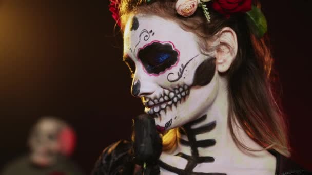 Okouzlující bohyně v kostýmu smrti a květinách věnec na pozadí studia, chovala se jako svatá Santa Muerte. La cavalera catrina dáma mrtvých s lebkou umění, mexická kultura. Ruční snímek. - Záběry, video