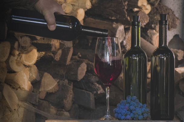 Випікання червоного вина з винограду Ізабелли у виноробстві. Соммельєр наливав десертне червоне вино з пляшки в скло. Збір врожаю винограду, виноробство. Культура десерту вина заповнює десертне вино повільним темпом. - Фото, зображення