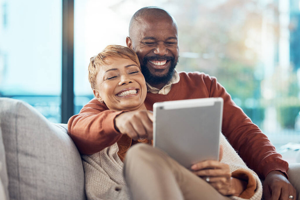 Couple, tablet and digital movie streaming of people on a home living room sofa with technology. Happy, relax and funny video watching of a woman and man on a home lounge sofa with love together. - 写真・画像