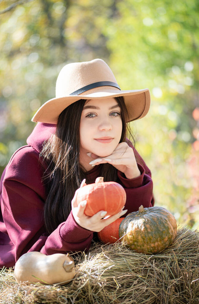 Caucasienne adolescent fille assis dans le parc d'automne. Elle tient de la citrouille orange dans ses mains. Saison d'automne - Photo, image