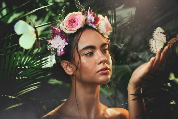 Beauty, flowers and butterfly with a model woman in studio on a forest or amazon background for wellness. Nature, spring and luxury with an attractive young female posing to promote natural care. - Foto, Imagen